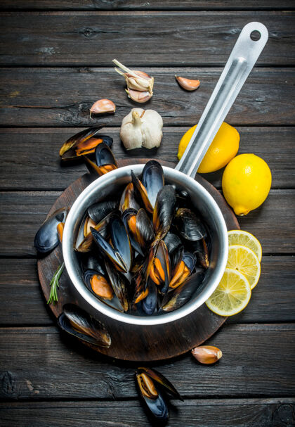 美味新鲜的海鲜蛤蜊配柠檬和大蒜放在乡村的桌子上木材平底锅市场