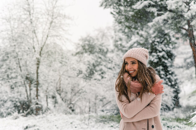 公园穿着暖和衣服的快乐女人站在雪林里 一边看一边享受冬日的周末女人乐观模糊