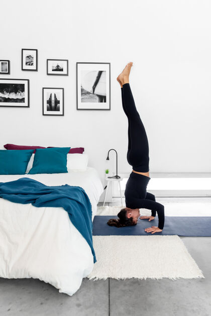 训练在舒适的家里练习三脚架姿势的健康女人（萨拉姆巴-西萨萨纳ii）瑜伽锻炼卧室