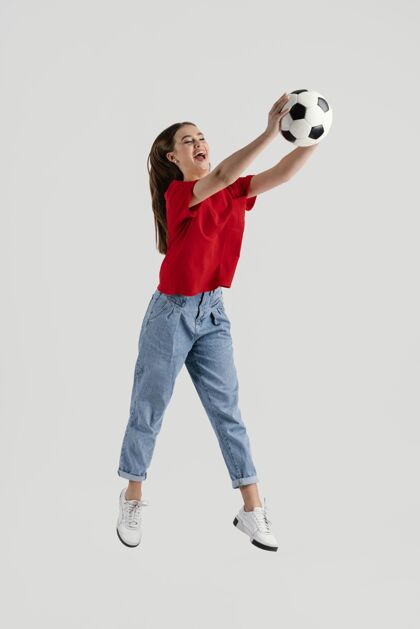 跳跃年轻漂亮的女子用足球跳跃女人美丽模特