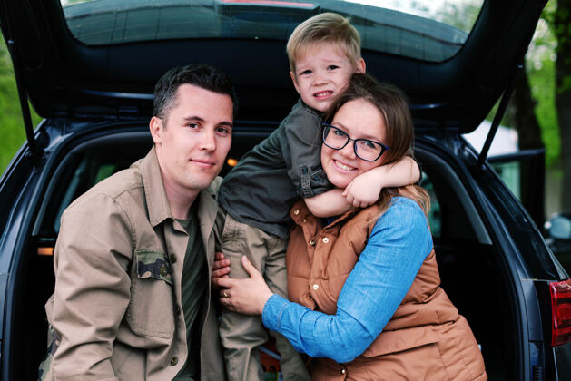 城市夫妻俩带着他们的小儿子在开着的越野车后备箱里停车儿子孩子女人