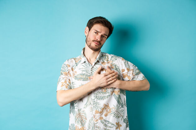 帅哥穿着夏威夷衬衫的热情浪漫的男人 手牵手 同情地看着 相爱 站在蓝色的背景上衬衫人脸