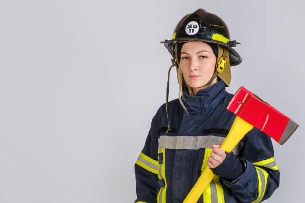 成人穿消防制服的年轻女子拿着斧头勇敢骄傲勇气