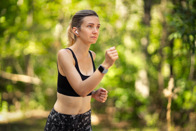 运动员美丽的年轻女子在绿色的森林里奔跑运动能量森林