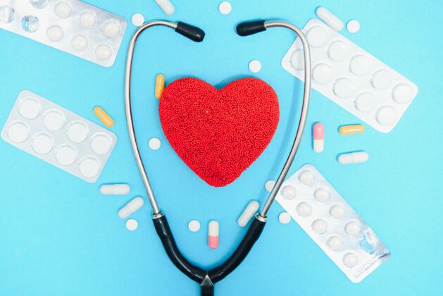 药物蓝色背景上的心脏和听诊器特写 俯视图全球卫生保健概念关心心脏健康用药片和安瓿治疗平板药房听诊器