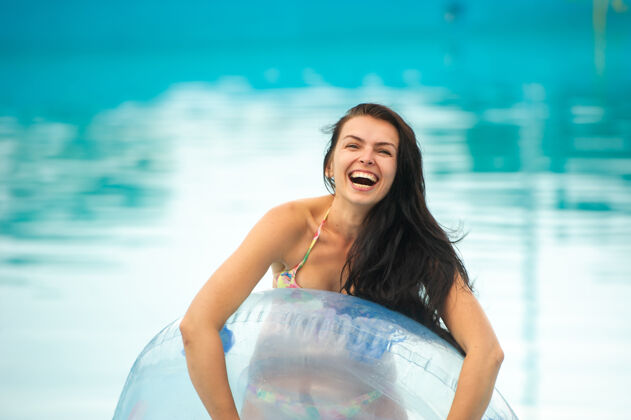 性感一个穿着比基尼的女人 带着一个橡皮充气圈 夏天在游乐园的游泳池里玩得很开心搞笑飞溅不寻常