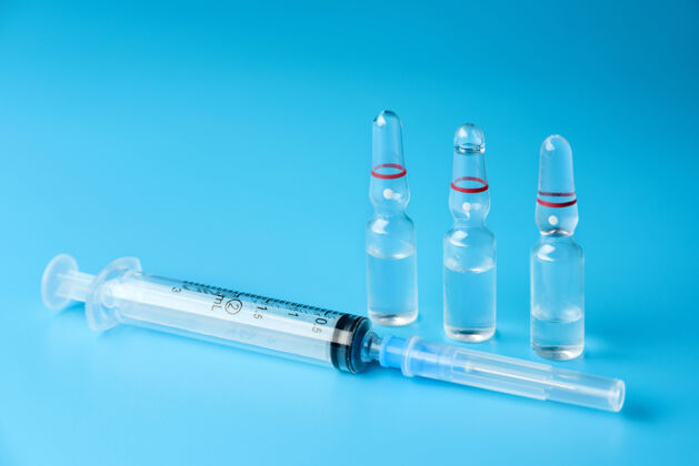 瓶子注射器和三个玻璃安瓿 蓝色表面有药物安瓿化学药品