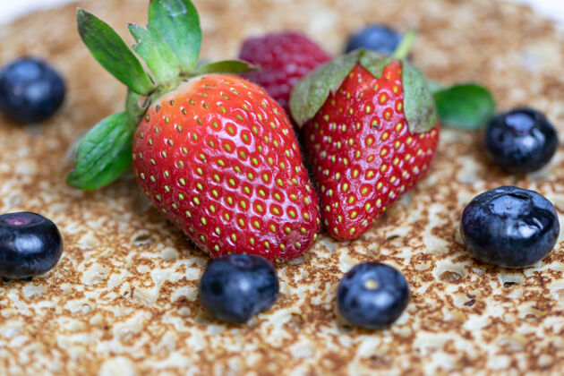 新鲜成熟多汁的草莓和蓝莓躺在美味的煎饼上俄罗斯料理国家菜 带新鲜浆果蓝莓特写成熟