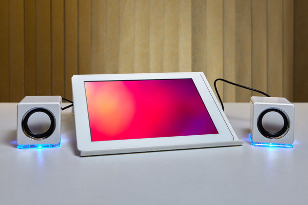 平板电脑桌上的平板电脑安装在平板电脑支架上 并连接到两个带led照明的白色小扬声器上电子数据扬声器