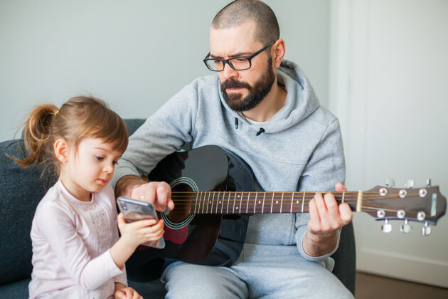 看小女孩在电话里给她父亲看一首歌男人在为她弹吉他房子房间乐器
