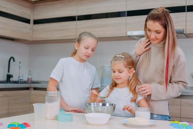 孩子妈妈在厨房教女儿们做面团在一起炒鸡蛋室内
