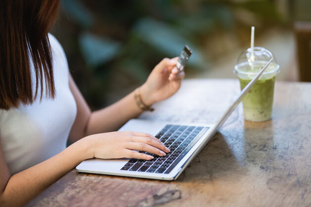 个人年轻女性使用笔记本电脑和信用卡在线购物 电子商务概念成人工作房子