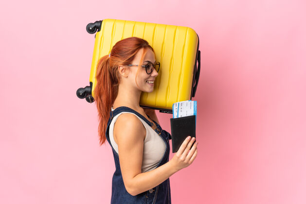 机票一个带着手提箱和护照的俄罗斯女人在度假时被隔离在粉红色的房间里旅行者女人护照