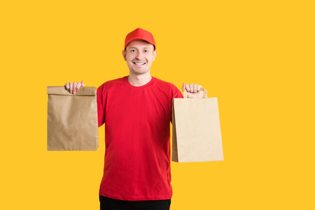包装穿着红色制服 手拿工艺包的快递员在黄色上下快餐订单制服男食品