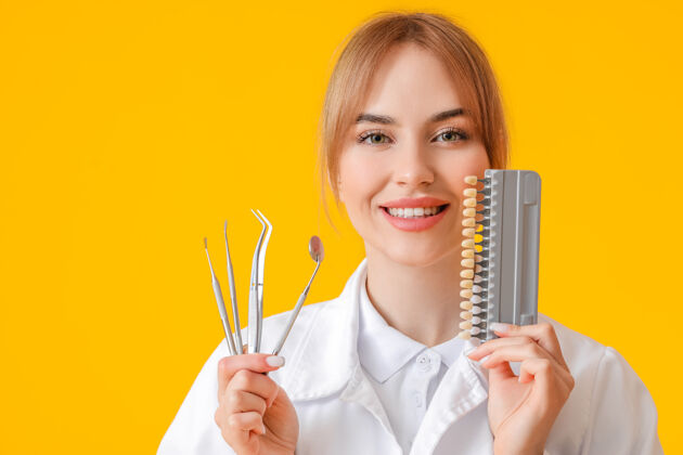 口腔女牙医用工具和牙齿颜色表在黄色表面预防医疗牙齿