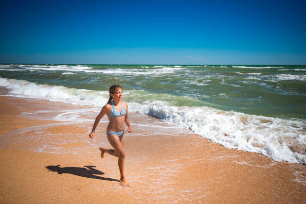 享受在一个阳光明媚 温暖的夏日里 快乐活泼的小女孩在狂风暴雨的海浪上跳跃阳光跳跃飞溅