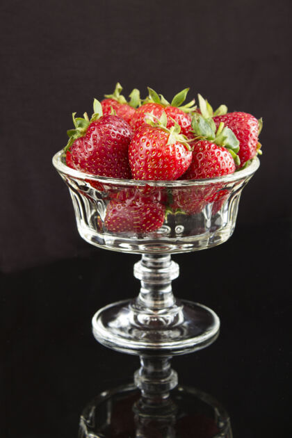 碗草莓放在黑墙上的玻璃花瓶里位置垂直特写早餐自然新鲜