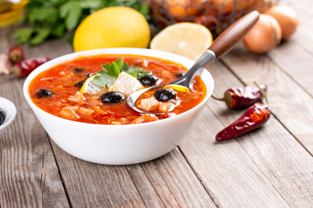 木头传统的俄罗斯苏利安卡汤与肉 香肠 腌黄瓜和橄榄一起煮在木桌上 留有复制空间健康汤西红柿