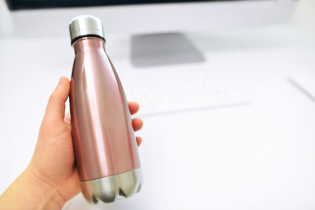 液体男性的手从办公桌上拿出一个环保的钢瓶来装水金属水瓶塑料瓶子包装