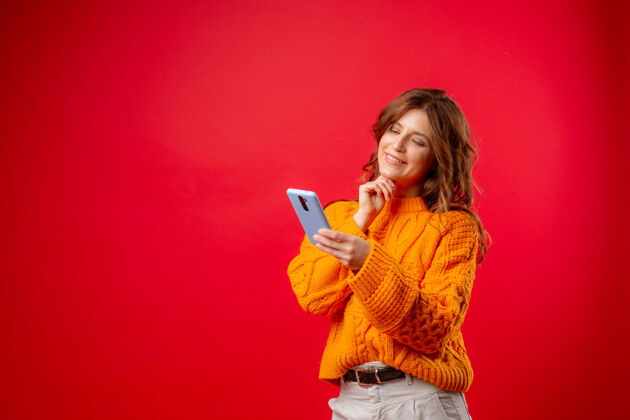 休闲一个穿红衣服的年轻女子拿着手机在打信息技术女性电话
