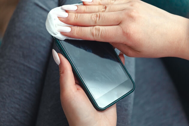 护理年轻女子用抗菌凝块清洗手机屏幕酒精卫生防护