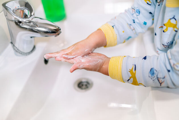 水槽穿着睡衣的孩子们的手在带水龙头的浴室水槽里用很多肥皂水洗手每天健康睡衣