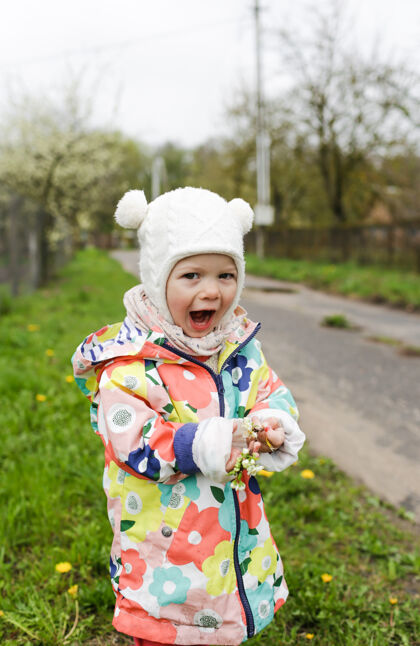 快乐一个穿着鲜艳夹克的小女孩在外面的春天里开心地笑着 手里拿着一根春白的树枝花孩子我的幸福夹克小有趣