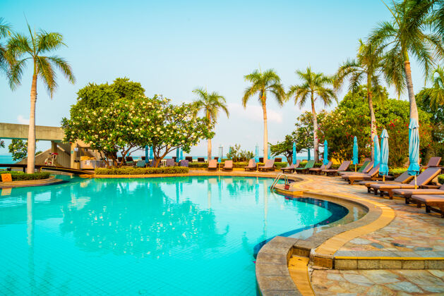 棕榈游泳池周围有椅子 游泳池和伞 还有椰子树树.假日还有度假的概念自然户外椰子