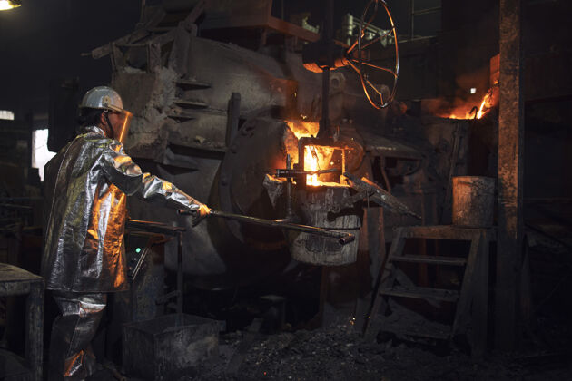 熔融铸造工人把热的钢倒进桶里进行金属铸造铝保护火花