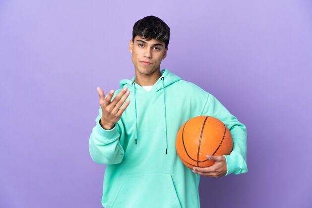 来在孤立的紫色背景上打篮球的年轻人邀请我一起去手高兴你来了球比赛球员