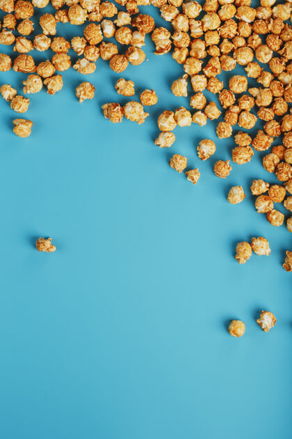 许多焦糖爆米花由一个蓝色背景上的波纹 在一个框架的形式小吃电影玉米