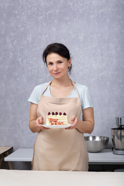 厨师糕点厨师女士拿着一个带浆果的蛋糕甜食食品浆果