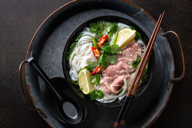米粉Pho-bo越南汤配牛肉和米粉 深色背景 顶视图菜碗传统