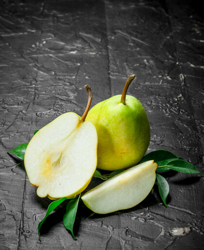 美味黑木桌上放着几片熟透的梨叶块新鲜营养