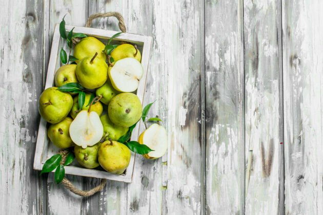 素食主义者新鲜的梨子和叶子放在木桌上的托盘上一半多汁甜点