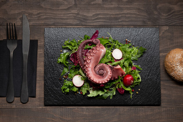 烹饪在木制的石板上用色拉炖章鱼触须桌面查看叉子食物菜
