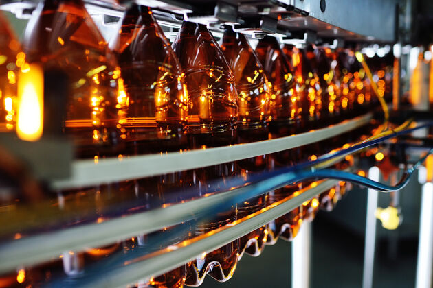 卷低酒精饮料 苏打水和向日葵用塑料瓶的工业生产油空以棕色pet瓶为背景的现代化设备制造工业设备