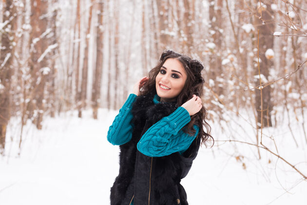 圣诞节美丽的年轻女子行走在冬雪的大自然中微笑风帽明亮