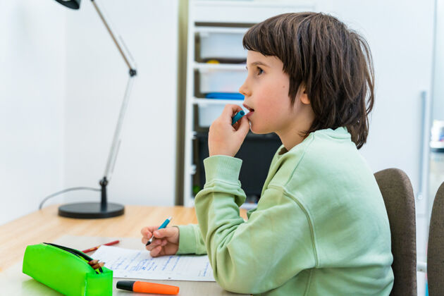 铅笔坐在课桌旁做作业的小学生家集中思考任务的孩子兴趣.家庭教育教育写作孩子人