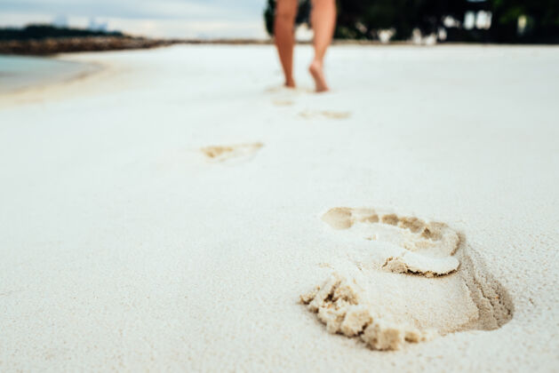 休闲赤脚在沙滩上的沙滩上行走印记动机沙滩