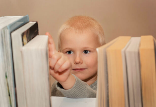 发展小男孩从书架上拿书室内兴趣图书馆