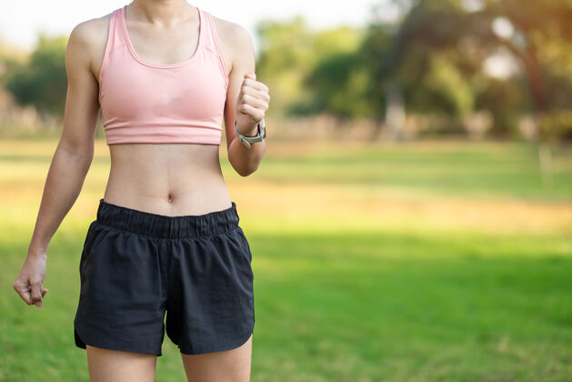 女孩穿着粉色运动服的年轻成年女性在公园户外伸展肌肉 运动女性热身准备跑步和慢跑早上好健康 健身 运动和工作生活平衡概念穿着训练跑步