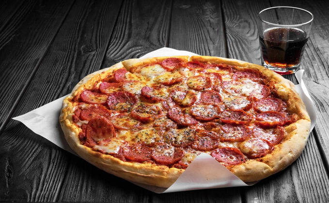传统的黑木板上的意大利香肠披萨 传统的意大利披萨 一杯可乐香肠小吃餐桌