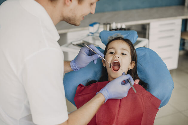 美丽小女孩坐在口腔科的座位上张着嘴 而她的儿科牙医正在做牙齿检查牙科牙科脸