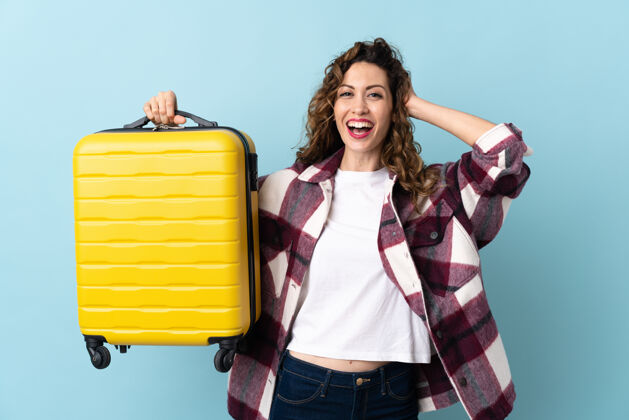 冒险年轻的白种女人孤独地在蓝色的度假旅行箱和惊喜手提箱行李手势