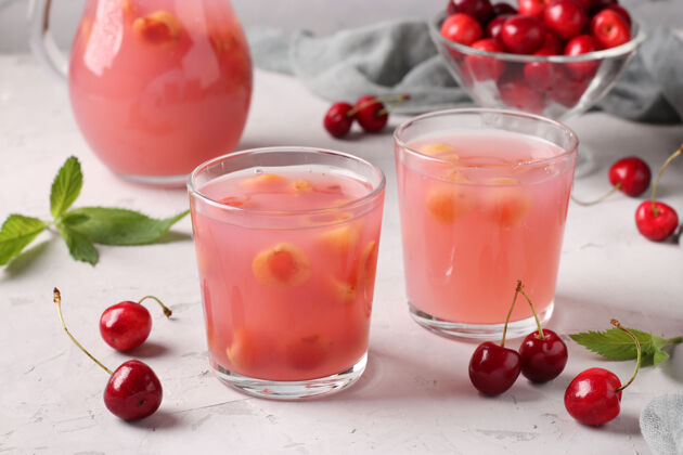 草药基塞尔用甜樱桃装在两个杯子里 罐子放在灰色的表面 水平格式 特写传统调味料液体