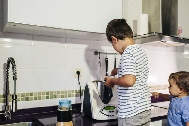 快乐一个孩子在用厨房机器人做煎饼男人小帮助