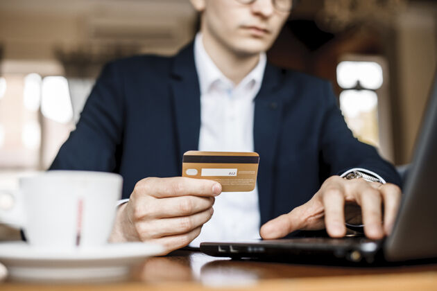 客户年轻帅哥在一家漂亮的餐厅用信用卡和笔记本电脑在网上购物信贷支付笔记本电脑
