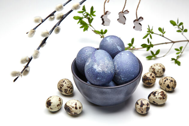 大理石一只碗里有彩绘的鸡和鹌鹑蛋 还有带木制玩具兔子的阴阳柳枝复活节彩蛋传统壳