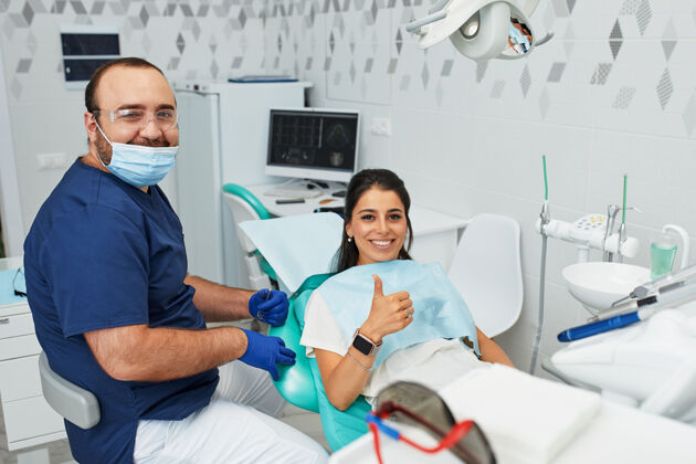 专家人医口腔保健理念-快乐男牙医在牙科诊所向女患者展示工作计划坐姿患者办公室